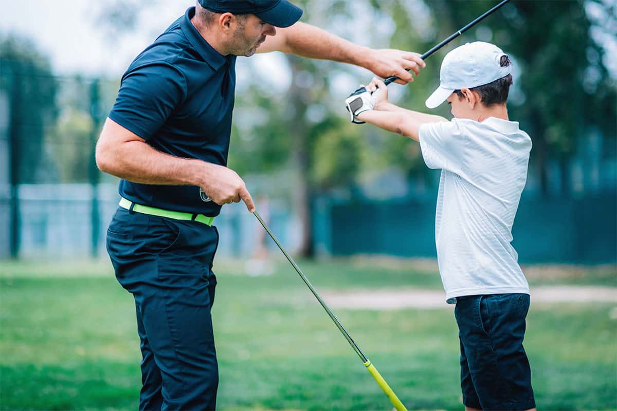 Golf Training Instructor Teaching Child